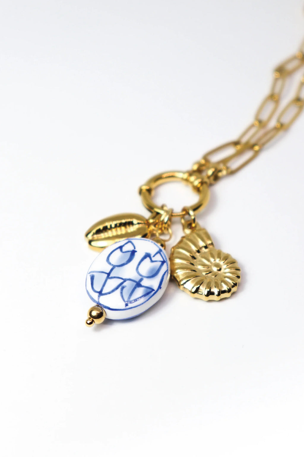 Gold necklace with a blue and white pendant on a white background