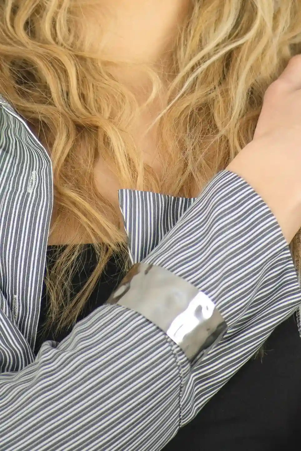 Close-up of a person wearing a striped shirt with rolled-up sleeves, focusing on the cuff.