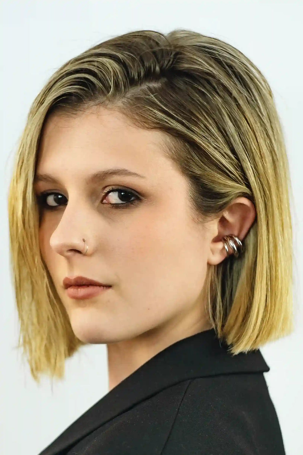 Woman with a stylish haircut and earrings against a plain background