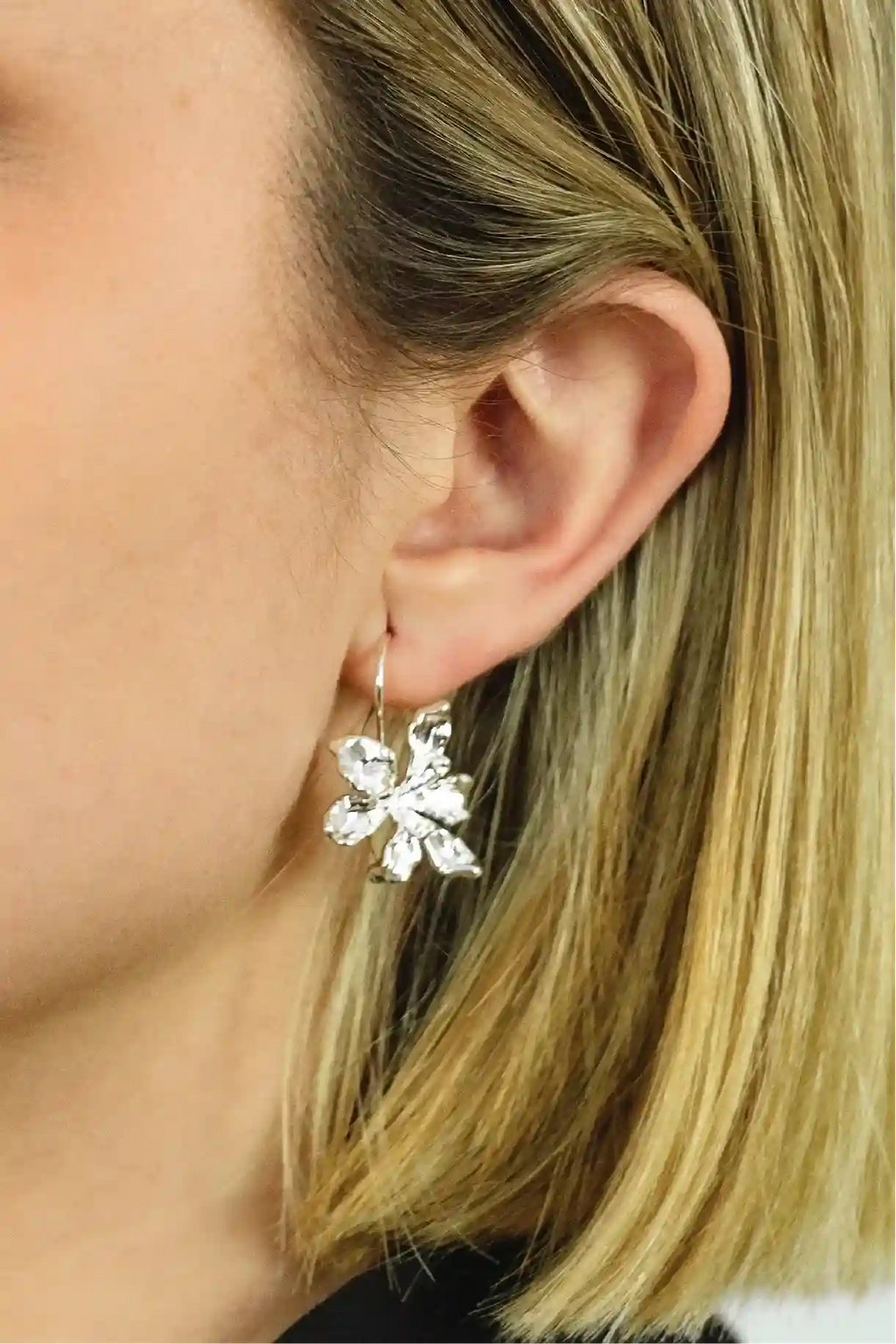 Close-up of a person wearing a silver floral earring.