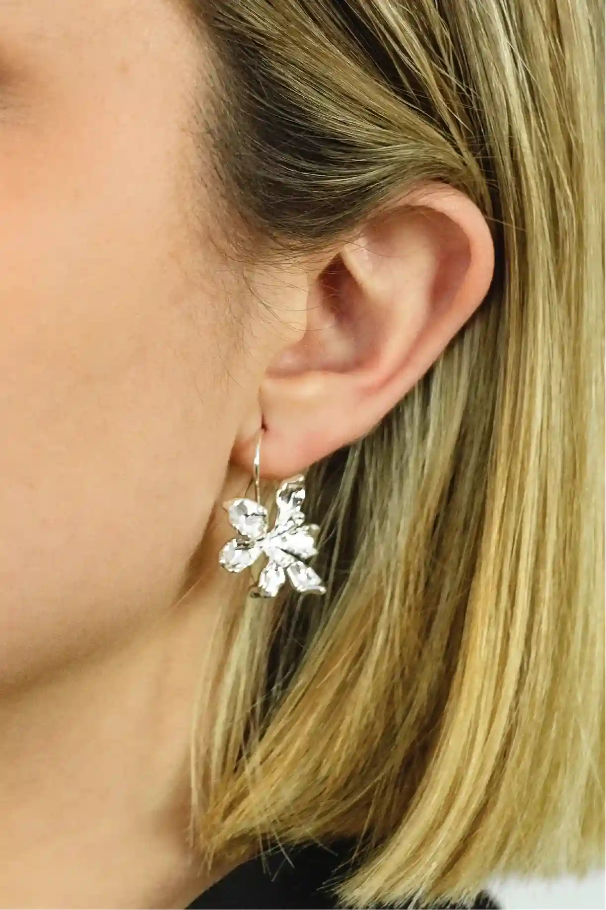 Close-up of a person wearing a silver floral earring.