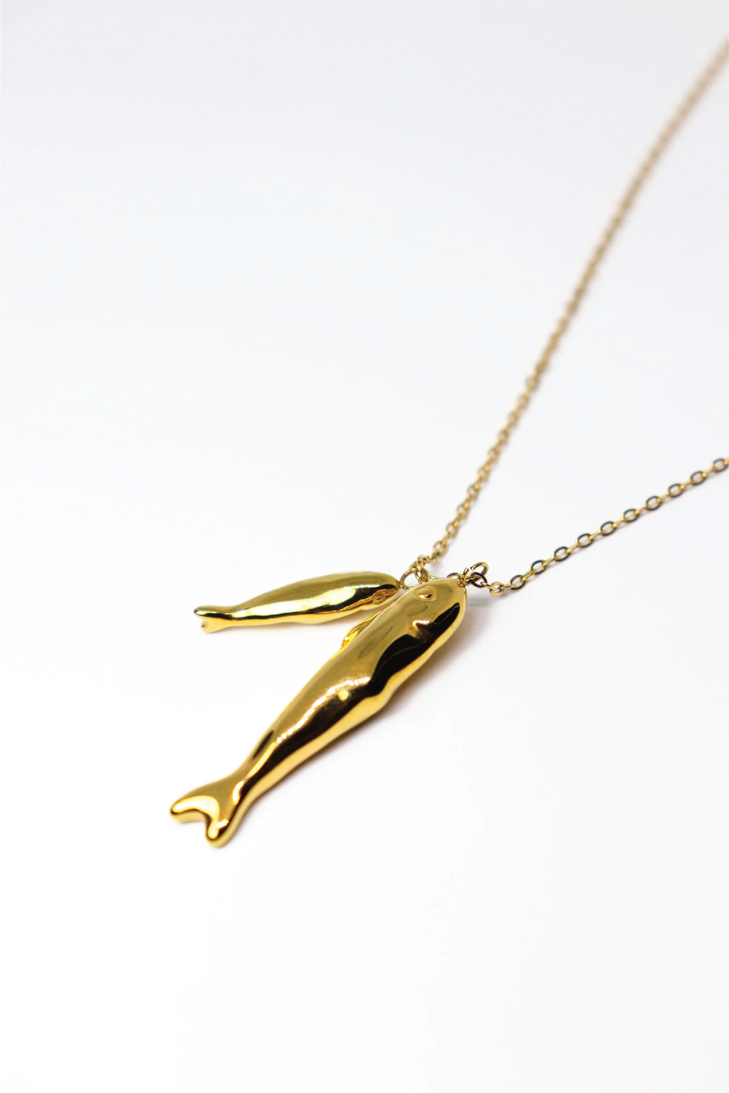 Gold dolphin pendant necklace on a white background