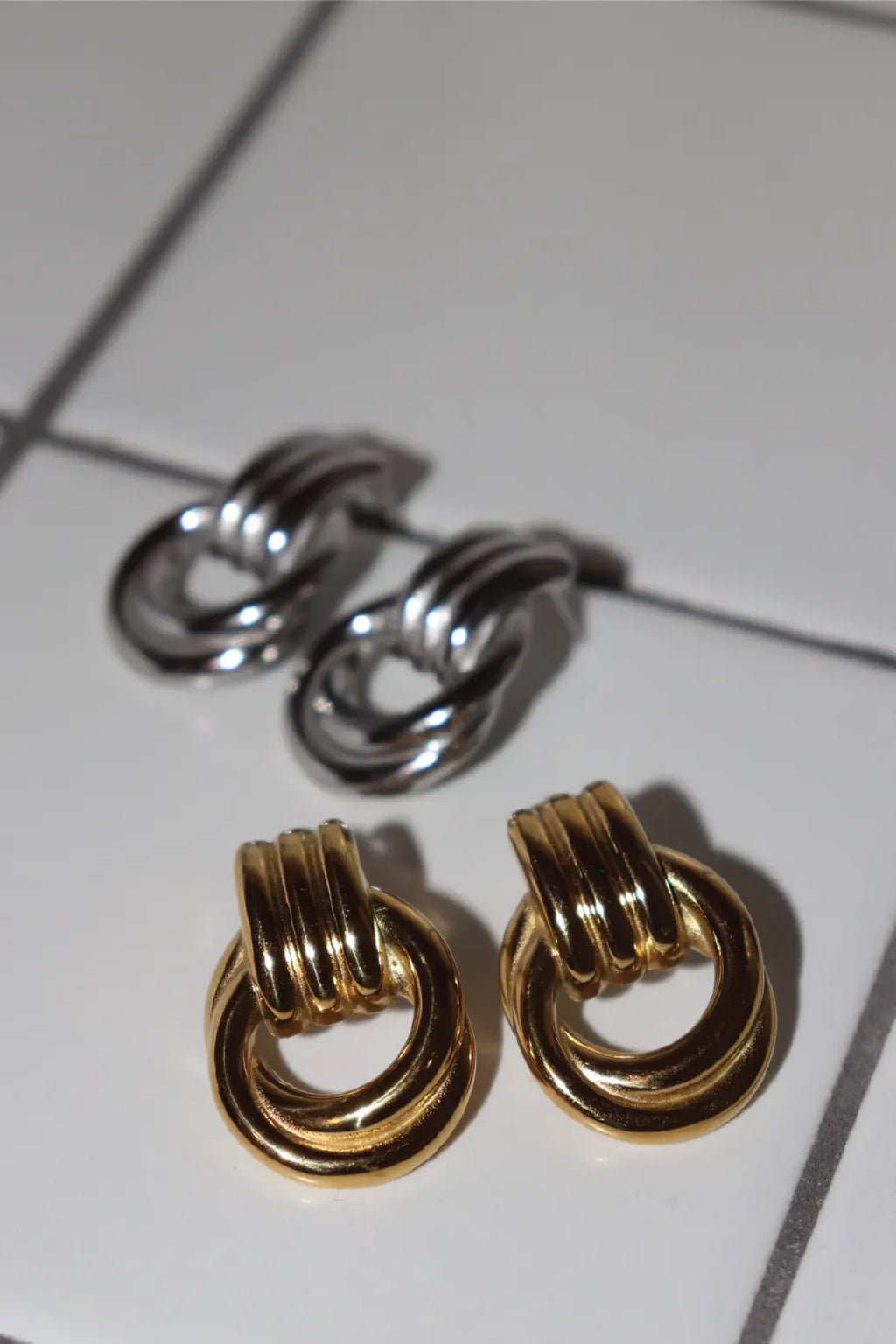 Pair of gold and silver earrings on a tiled surface