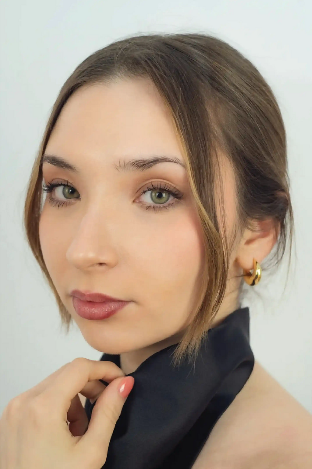 Close-up of a woman with a neutral expression against a light background